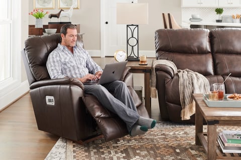 man sitting in brown recliner chair while shopping online