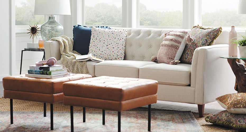 cream tufted sofa with attached cushions and leather ottoman