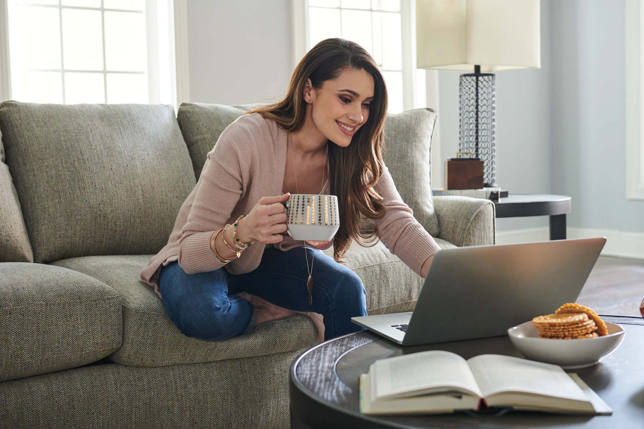 woman shopping for furniture online with cup of coffee